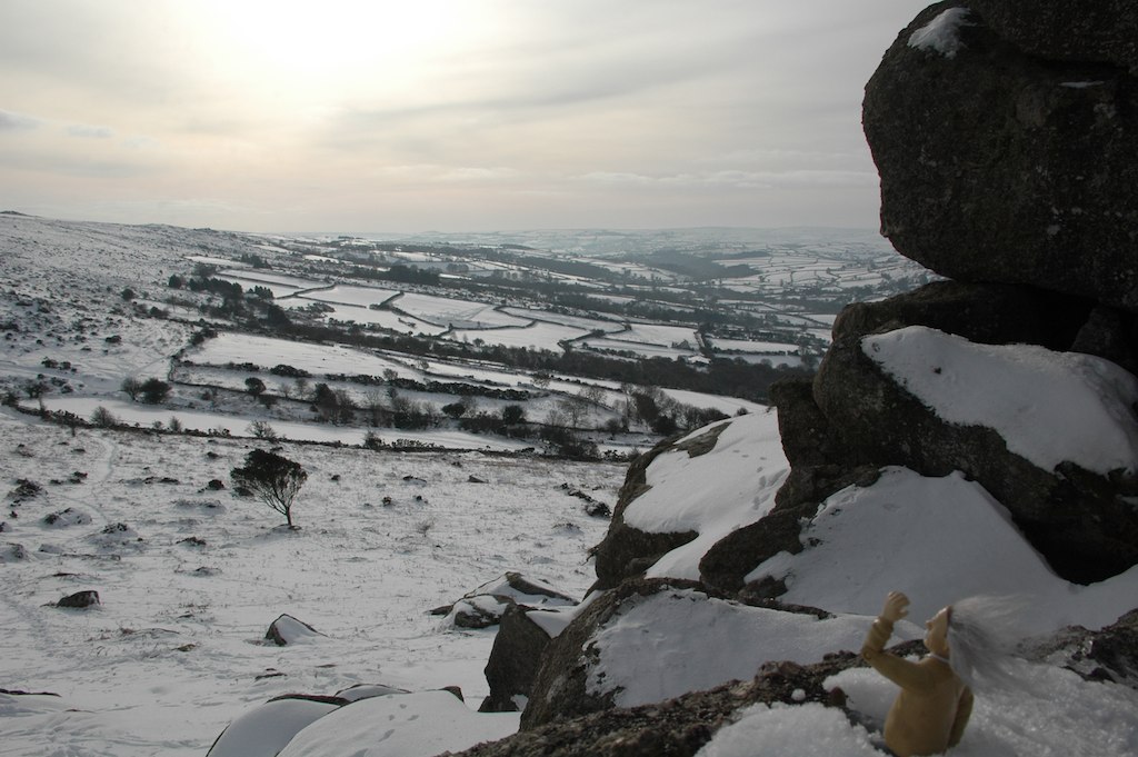 Snow-covered Dartmoor viewed from a granite tor, patchwork fields stretching into the distance